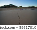 Little toddler running on the sandy beach leaving foot prints behind. 59617810