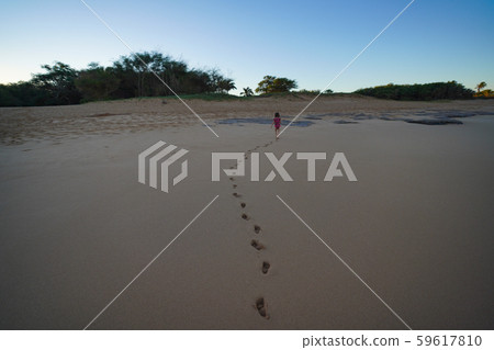 Little toddler running on the sandy beach leaving foot prints behind. 59617810
