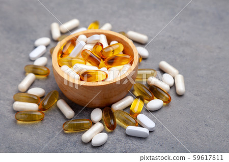 Assortment scattered pharmaceutical medicine vitamins, pills, drugs in wooden bowl on gray 59617811