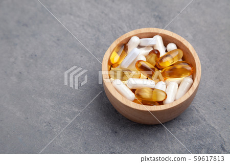 Assortment scattered pharmaceutical medicine tablets, pills, drugs in wooden bowl on gray background 59617813
