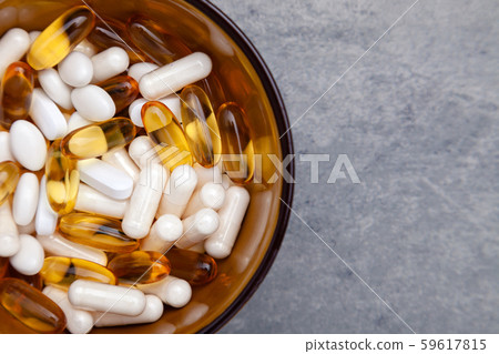 Tablets, pills, capsules, drugs in brown bowl on gray background. Sport, healthy lifestyle, medicine 59617815