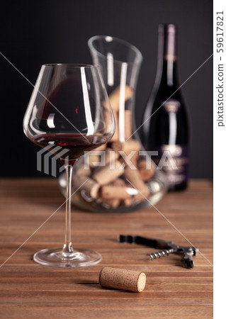 Crystal red wine glass, bottle, corkscrew, opener, sommelier knife, transparent decanter, corks on 59617821