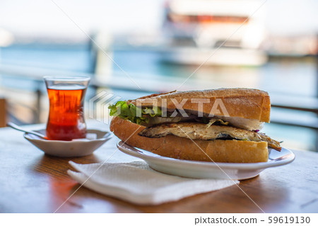 Istanbul fish sandwich. Burger with fried fish. Turkish tea with Balik Ekmek. Blurred background 59619130