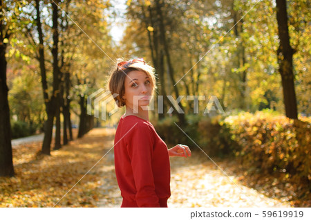 Young and beautiful girl with short hair and red sensual lips is posing against alley of the trees Young and beautiful girl with short hair and red sensual lips is posing against alley of the trees 59619919