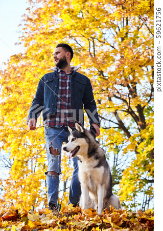 Hipster stylish guy with his husky dog in autumn 59621756