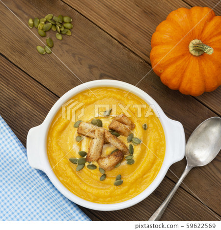 Pumpkin soup in a bowl,with fresh pumpkin seeds. 59622569