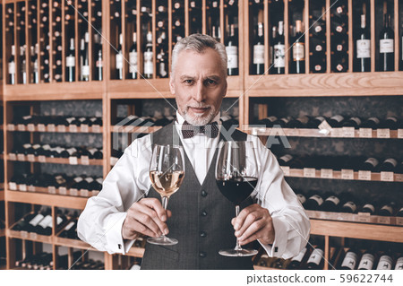 Sommelier Concept. Senior man standing with glasses of red and white wine smiling friendly Sommelier Concept. Senior man standing with glasses of red and white wine smiling friendly 59622744