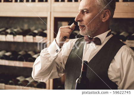 Sommelier Concept. Senior man standing opening wine bottle smelling cork concentrated close-up 59622745