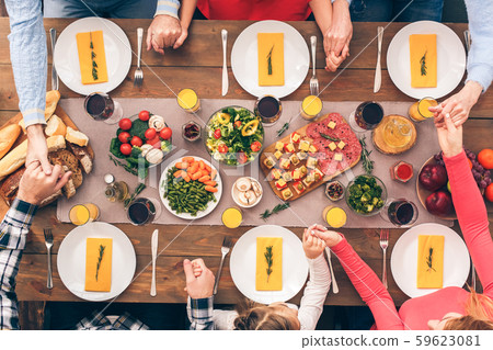 People sitting at home behind table, praying together before dinner 59623081