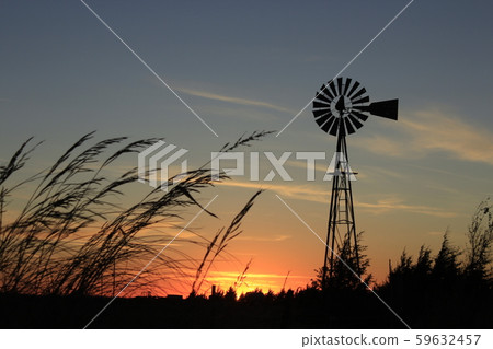 Kansas Colorful Sunset with a Windmill Silhouette with cloud's and tree's. 59632457