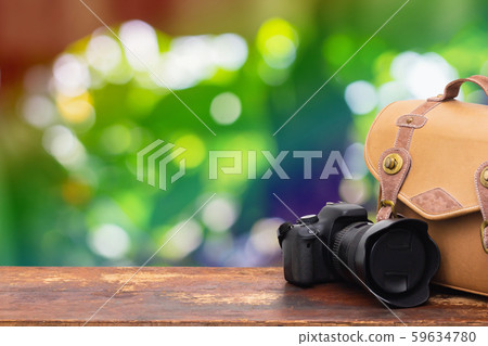Digital camera and camera bag on an old brown wooden table.Abstract nature green boke background. Digital camera and camera bag on an old brown wooden table.Abstract nature green boke background. 59634780