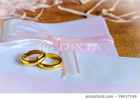 Duo golden wedding ring over invice card on wood Duo golden wedding ring over invice card on wood 59637349