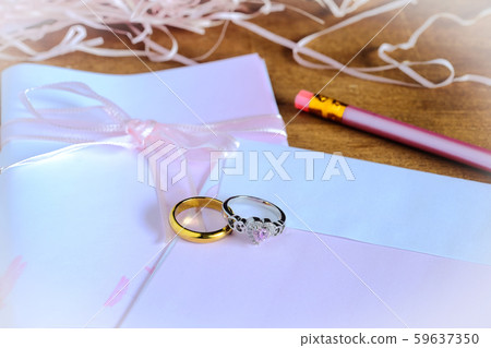 Duo golden wedding ring over invice card on wood 59637350