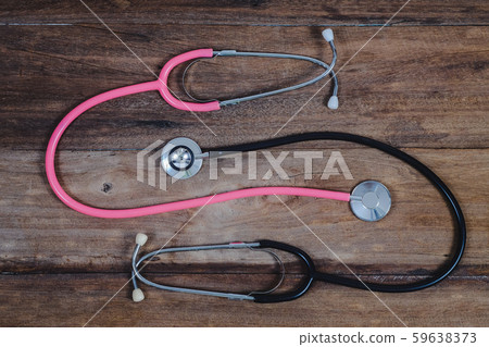 Pink and black Stethoscope on wood table. 59638373