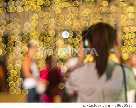 Defocus of unidentifield woman take a photo with blurry yellow light bulb. 59639553