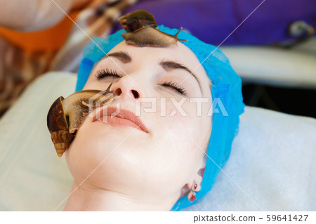 The cleansing facial at the beautician by snails Achatina. The girl at the beautician does Facials The cleansing facial at the beautician by snails Achatina. The girl at the beautician does Facials 59641427