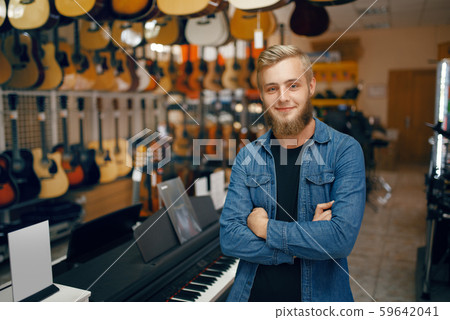 Young man poses at the showcase in music store Young man poses at the showcase in music store 59642041