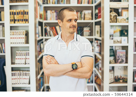 Adult man standing in library with crossed hands 59644314