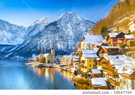 Classic postcard view of famous Hallstatt lakeside town in the Alps with traditional passenger ship on a beautiful cold sunny day with blue sky and clouds in winter, Salzkammergut region, Austria Classic postcard view of famous Hallstatt lakeside town in the Alps with traditional passenger ship on a beautiful cold sunny day with blue sky and clouds in winter, Salzkammergut region, Austria 59647784