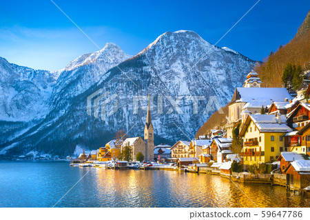 Classic postcard view of famous Hallstatt lakeside town in the Alps with traditional passenger ship on a beautiful cold sunny day with blue sky and clouds in winter, Salzkammergut region, Austria Classic postcard view of famous Hallstatt lakeside town in the Alps with traditional passenger ship on a beautiful cold sunny day with blue sky and clouds in winter, Salzkammergut region, Austria 59647786