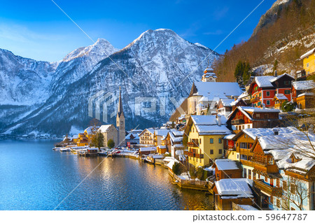 Classic postcard view of famous Hallstatt lakeside town in the Alps with traditional passenger ship on a beautiful cold sunny day with blue sky and clouds in winter, Salzkammergut region, Austria Classic postcard view of famous Hallstatt lakeside town in the Alps with traditional passenger ship on a beautiful cold sunny day with blue sky and clouds in winter, Salzkammergut region, Austria 59647787
