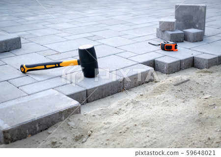 The master in yellow gloves lays paving stones 59648021