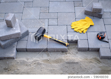 The master in yellow gloves lays paving stones 59648030