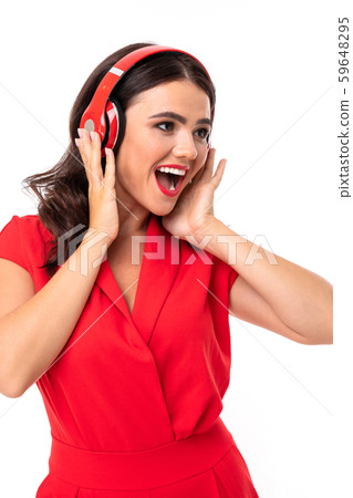A young woman with red lips listens to music in headphones and smiles 59648295
