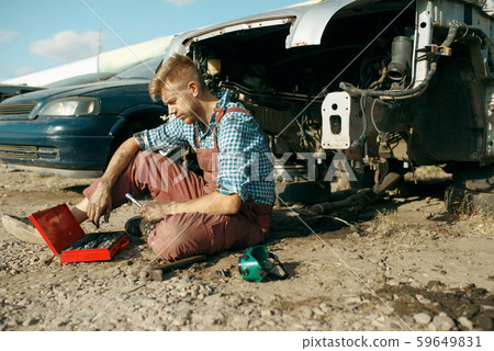 Male mechanic in welding glasses on car junkyard Male mechanic in welding glasses on car junkyard 59649831