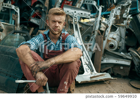 Dirty male repairman with wrench on car junkyard 59649910