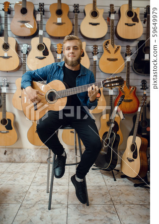 Guitarist plays on acoustic guitar in music store Guitarist plays on acoustic guitar in music store 59649979