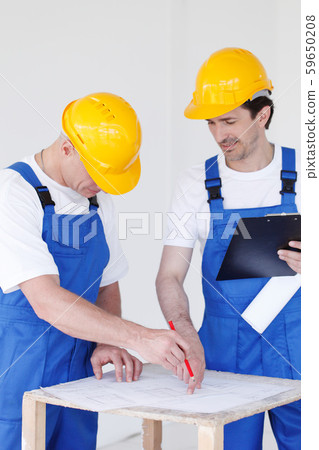 Builders in hardhats with blueprint 59650208