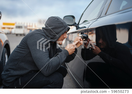 Car thief with screwdriver breaking door lock Car thief with screwdriver breaking door lock 59650273