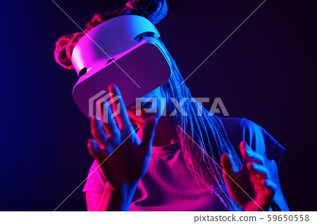 Woman is using virtual reality headset. Neon light studio portrait. Woman is using virtual reality headset. Neon light studio portrait. 59650558