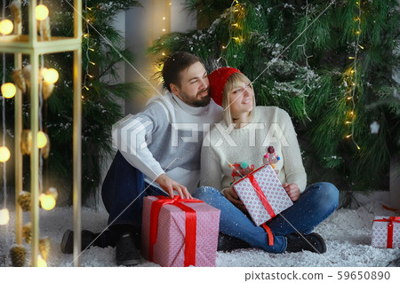 A man with a woman in a photo Studio on the background of an artificial Christmas tree and snow A man with a woman in a photo Studio on the background of an artificial Christmas tree and snow 59650890