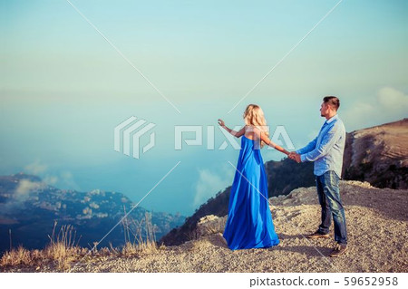 A couple in love in blue outfits on top of a mountain and the whole world at a glance 59652958
