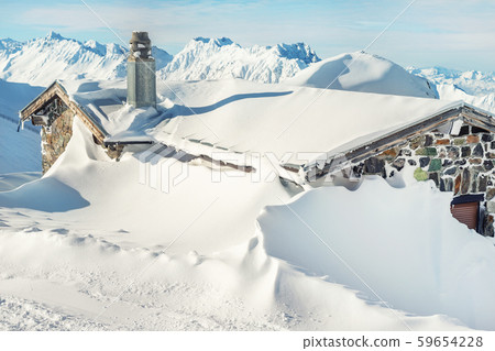 Scenic Highland alpine old abandoned stone hut with chimney snowbound by thick snow layer after 59654228