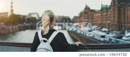 Panoramic rear view of adult woman tourist with backpack enjoying historic warehouse district 59654788