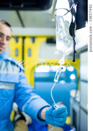 Gloved paramedic checking dropper while going to give first aid to sick person 59657492