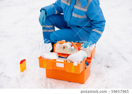 Young paramedic in workwear and gloves checking medicine and first aid items 59657965