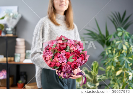 Red tones Beautiful bouquet of mixed flowers in womans hands. the work of the florist at a flower 59657973