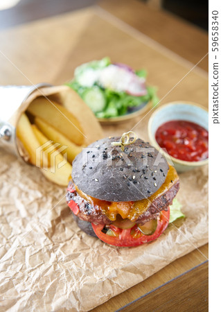 Cheeseburger with lettuce, tomato, fries, and melted cheese. The table in the restaurant. Unhealthy Cheeseburger with lettuce, tomato, fries, and melted cheese. The table in the restaurant. Unhealthy 59658340