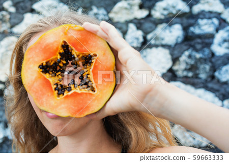 Happy young woman looking through ripe papaya 59663333