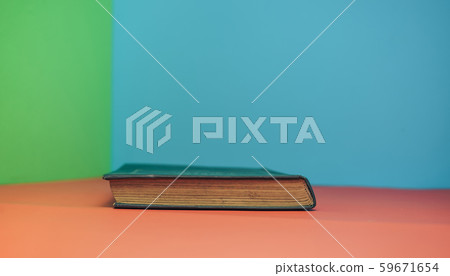 Book on a red table and green blue background. 59671654
