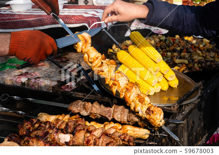 Two hands turning skewers with pieces of juicy Two hands turning skewers with pieces of juicy 59678003