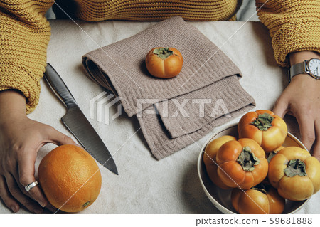 Hand holding dish with fresh orange persimmons 59681888