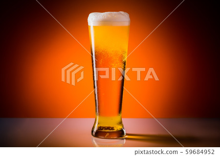 Beer glass with drops on a orange background. 59684952