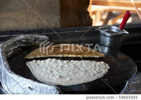 Traditional Turkish gozleme stuffed with meat and cheese are fried on the stove 59685885