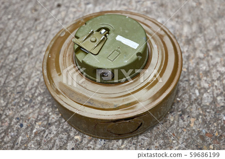 Khaki colour modern anti-tank mine lies on concrete surface 59686199