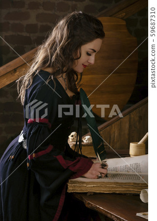 Medieval Woman in a dress near the desk with a pen in hand. On a table lay old book  59687310